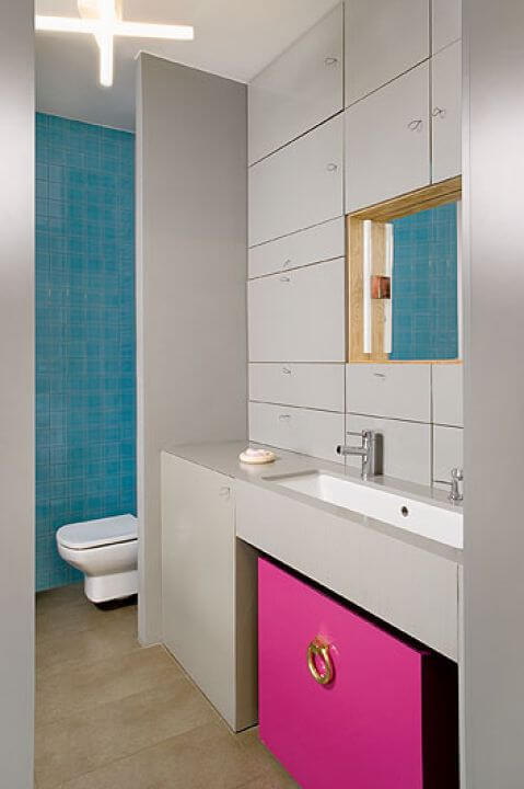 Żeby szarość nie rządziła w domu, właścicielka zdecydowała się na morskie kafelki i amarantową szafkę.