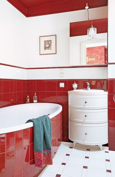 W łazience czerwień kafelków przełamana jest stylowymi białymi meblami.