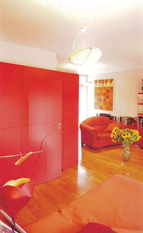 Czerwone panele świetnie się komponują z nowocześnie urządzoną sypialnią.