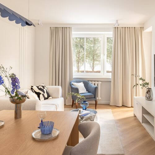 Jasny salon z jadalnią, lustrzaną szafą i designerską lampą w odcieniu burzowego błękitu