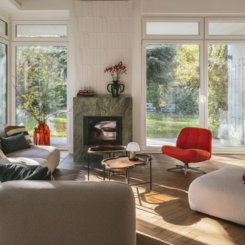 salon w stylu modern retro z  kominkiem obłożonym zielonym marmurem