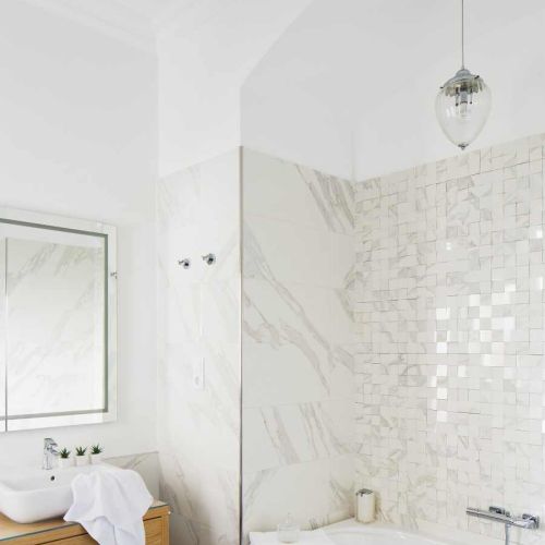 Choć dużo tu bieli, nie jest chłodno i nudno, a to dzięki mozaice nad wanną.