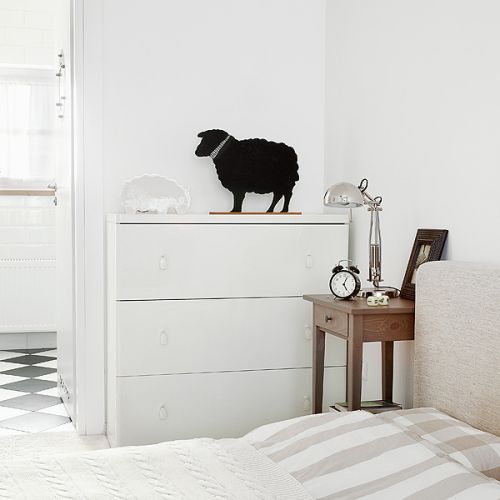 Biel przełamują pojedyncze meble w kolorze naturalnego drewna.