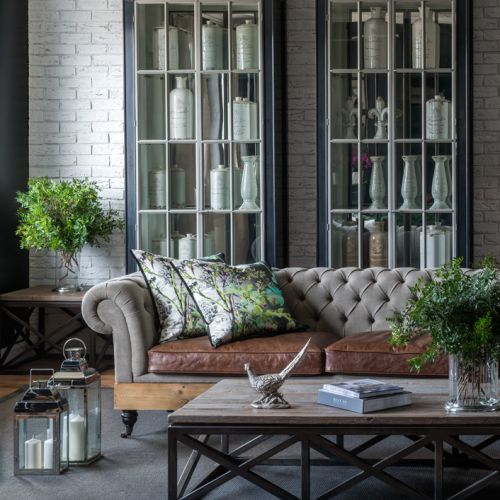 Ciemny kolor mebli w salonie warto przełamać jasną tapicerką sofy i np. wzorzystymi poduszkami.