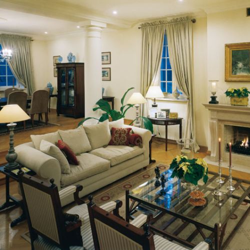 Do ognia w kominku z piaskowca przyciągają wygodne kanapy - widoczny za nimi stół to jadalnia, połączona przejściem z