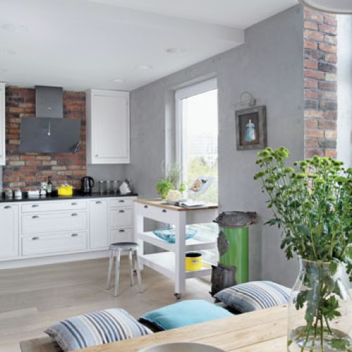 Do tradycyjnie wypalanej, holednerskiej cegły pasuje surowy drewniany stół. Nad kozą wisi obraz warszawskiej malarki