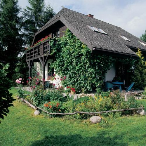 Dom otacza piękny ogródek. Powietrze, drewno i obrazy