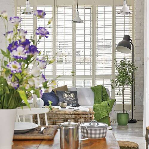 Dominującą biel przełamują delikatne zielenie oraz kolory dekoracji - także sezonowych kwiatów w wazonie.