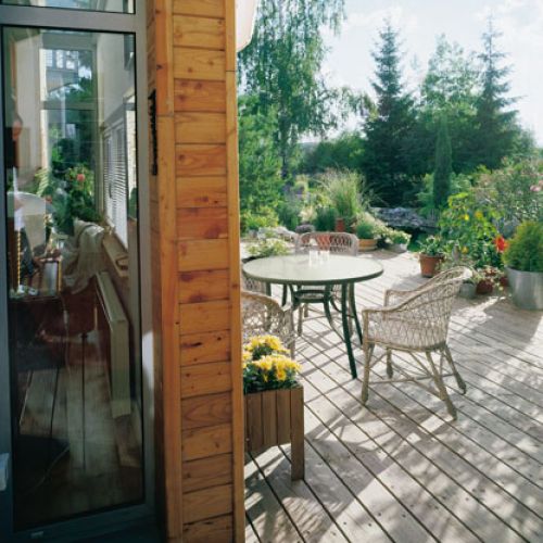 Drewnianego tarasu nie otaczają żadne barierki, jedynie rośliny w donicach. To daje poczucie przestrzeni.