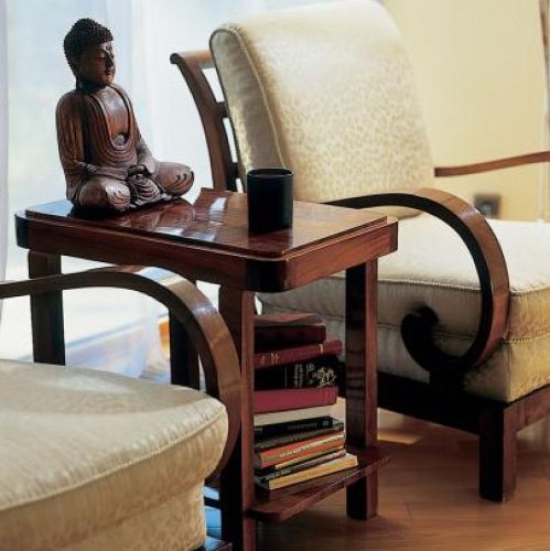 Drewniany posążek stoi na stoliku między dwoma fotelami.