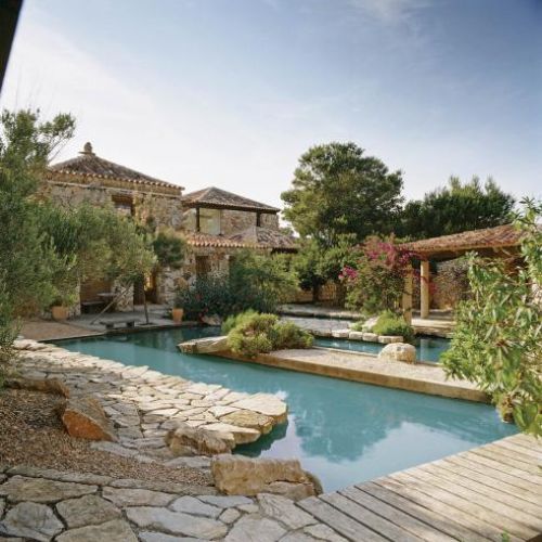 Dzięki nierównym brzegom i drewnianym tarasem basen komponuje się z ogrodem.