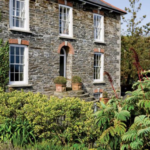 Dziewiętnastowieczny dom z kamienia zatopiony pośród wielkiego ogrodu.