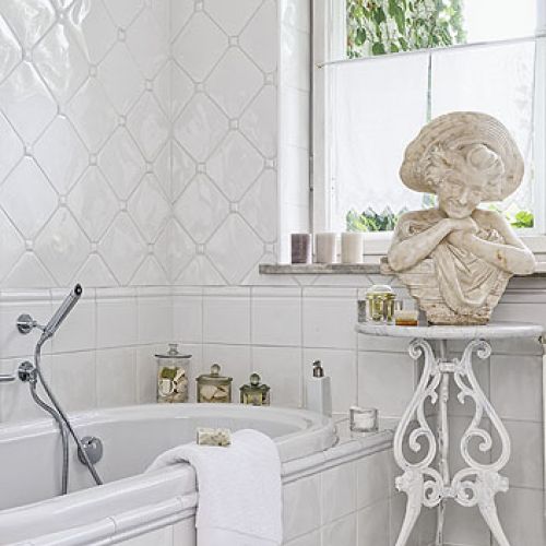 Łazienka w aranżacji rodem z Półwyspu Iberyjskiego: białe, hiszpańskie kafelki i XIX-wieczna rzeźba.