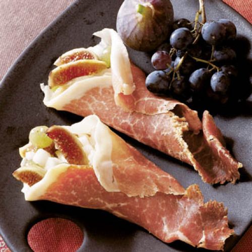 Jabłka, gruszki, winogrona i figi zawinięte w plastry szynki parmeńskiej.
