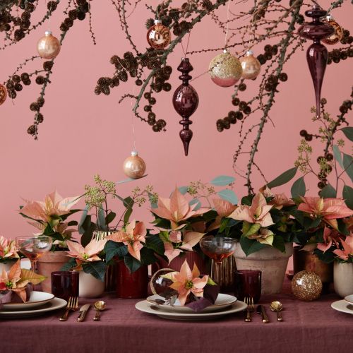 Świąteczna dekoracja stołu: nad stołem podwieszono dużą gałąź, która została świątecznie przystrojona. Dekorację stołu tworzą