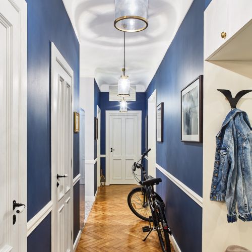 BIAŁE LISTWY SZTUKATERYJNE NA GRANATOWEJ ŚCIANIE TWORZĄ POMYSŁOWĄ LAMPERIĘ. LAMPY – HUBSCH Z N S HOME.