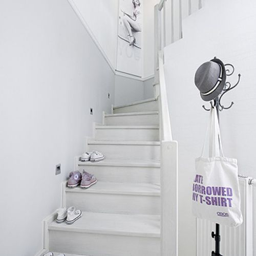 Jasno urządzone wnętrze, z kominkiem, ogromnymi oknami i drewnianym tarasem.