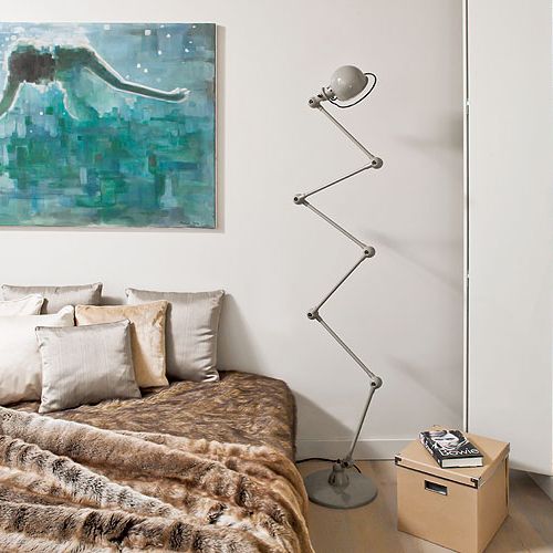 Jedyny kolorowy akcent w beżowo-szarej sypialni to obraz Mariusza Andryszczyka. Obok łóżka stoi kultowa lampa