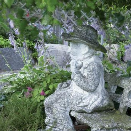 Kamienna ławka, na której siedzi kamienny człowieczek.