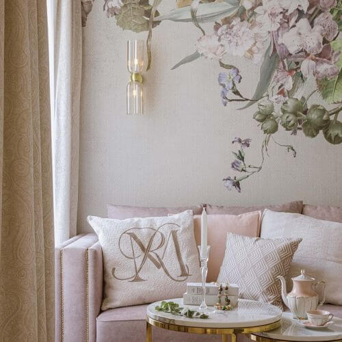 różowa sofa na tle tapety w kwiaty w salonie