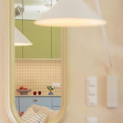 lampa wisząca odbijająca się w owalnym lustrze w jasnej ramie