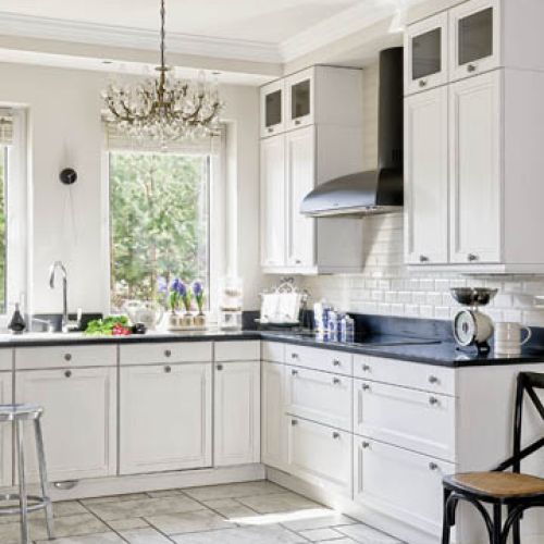 Kuchnia biało-czarna, z czarnym kamieniem na blatach, symetryczna, do samego sufitu.