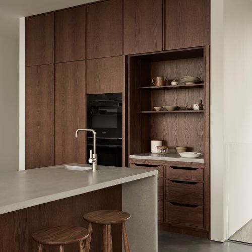 kuchnia z ciemnego drewna z wyspą i jasnym blatem