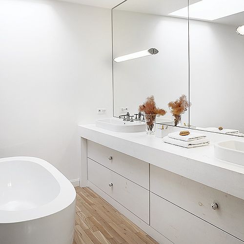 Lustra optycznie powiększają łazienkę. Na podłodze drewno.