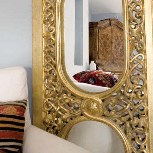 Lustro w złotej ramie dodaje sypialni blasku.