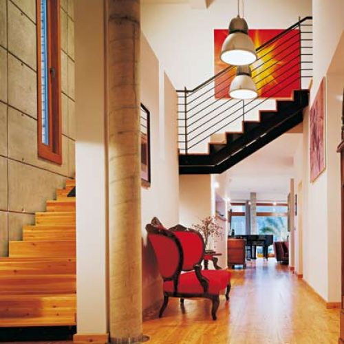 Mieszanka stylów i materiałów przynosi nieraz nadspodziewane efekty. Ciekawostką w holu jest betonowy słup, który