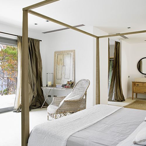 Mniej znaczy więcej. Proste łóżko z baldachimem, wiklinowe fotele i obrazy oparte o ścianę. I tak widoki są tu najważniejsze.