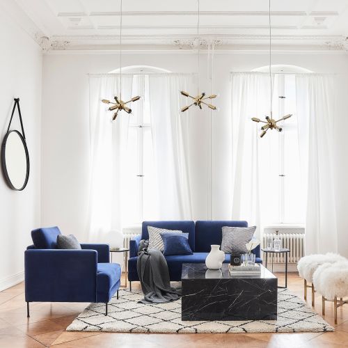 granatowa sofa i marmurowy stolik kawowy w salonie