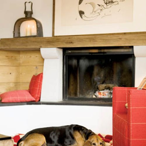 Na kominkowej ławie, wyłożonej czarnym łupkiem, niedbale rzucone kraciaste poduszki.