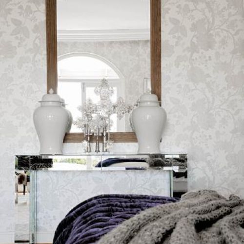 Na lustrzanej konsoli stoją dekoracyjne naczynia.