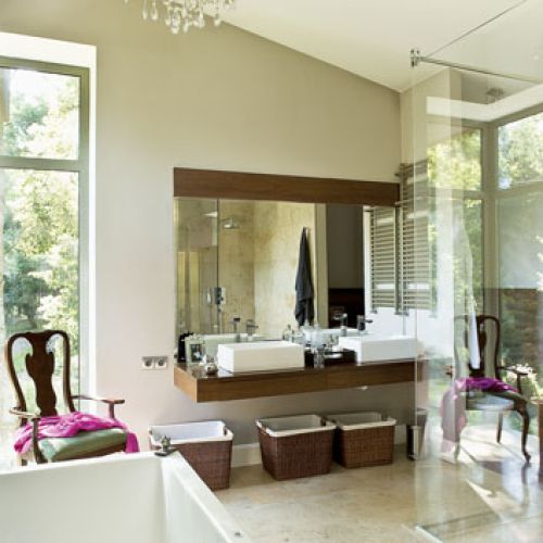 Na podłodze wapień, fornirowany blat pod umywalkami, drewniana podłoga i kosze nawiązują do stylu kolonialnego.