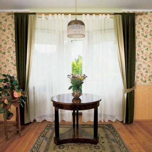 Nad okrągłym stolikiem wisi lampa. Sypialnia po angielsku