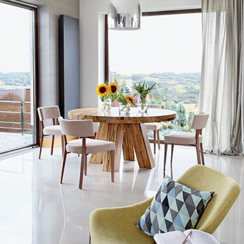 Nad orzechowym stołem, zrobionym na zamówienie, lampa Prandina. Fotel Mishell z Noti.