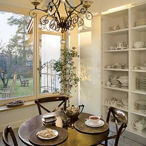 Nad stołem wisi elegancki żyrandol. Rezydencja strojna w antyki