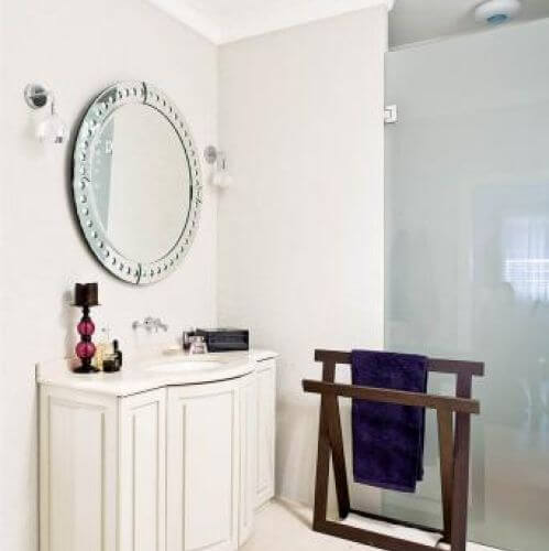 Nad umywalką okrągłe lustro. Apartament kosmopolityczny