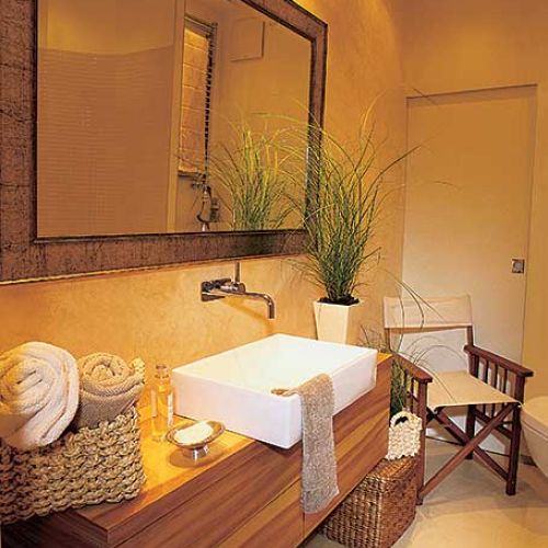 Nad umywalką wisi duże lustro w ciekawej ramie.