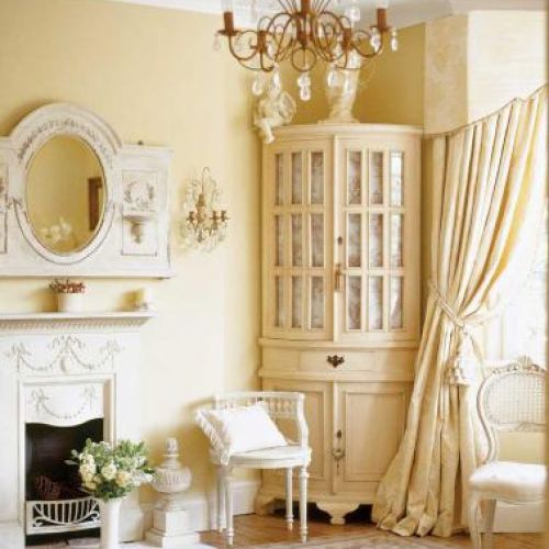 Narożna szafa, kominek i kryształowy żyrandol.