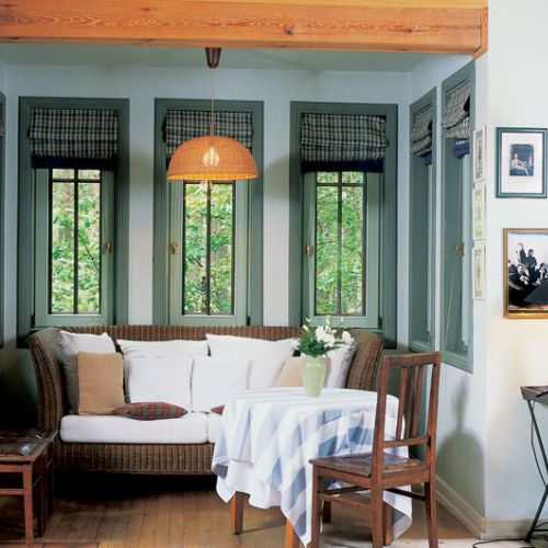 Niczym na letnisku - wiklinowa kanapa w przeszklonym wykuszu.