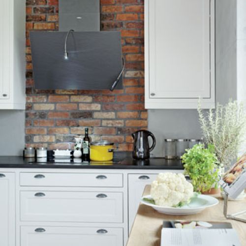 Nowoczesny okap, proste szafki kuchenne i tradycyjnie wypalana holenderska cegła.