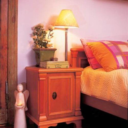 Obok nocnej lampki stoi świecznik- aniołek.