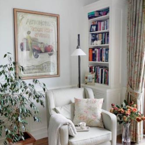 Obok regału stoi jasny fotel. Róże i falbanki