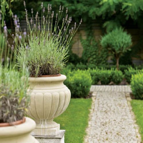 Ogrodowi klasyczny charakter nadają stylizowane na antyczne amfory donice i wysypane żwirem proste alejki.