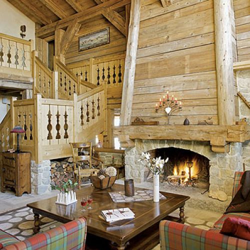 Otwarty, wysoki kominek z kamienia i świerkowego drewna, zaprojektowany przez architekta Nicolasa Perrin, ogrzewa cały