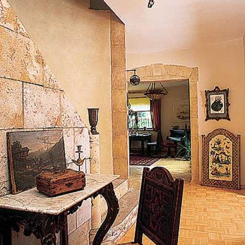 Pod kamienną ścianą stoi zdobiona konsola.