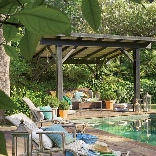 Pod zadaszeniem ustawiono wygodne kanapy sporo dekoracji roslinnych.