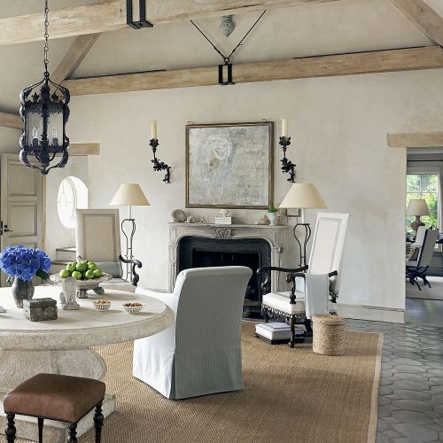 Podłogę w salonie wyłożono marokańskimi płytkami z terakoty, na nich dywan z sizalu. Przy kominku wysokie fotele w stylu